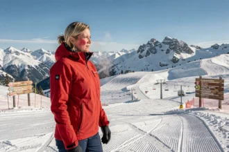 Skieuse au sommet d'un grand domaine skiable en Savoie avec vue panoramique sur les remontées mécaniques et les pistes enneigées