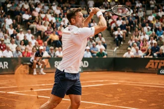 Joueur de tennis professionnel en plein service sur un court en terre battue lors d'un tournoi ATP