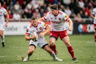 Deux joueurs de rugby en duel lors d'un match de Fédérale 1, plaquage en cours sur pelouse verte